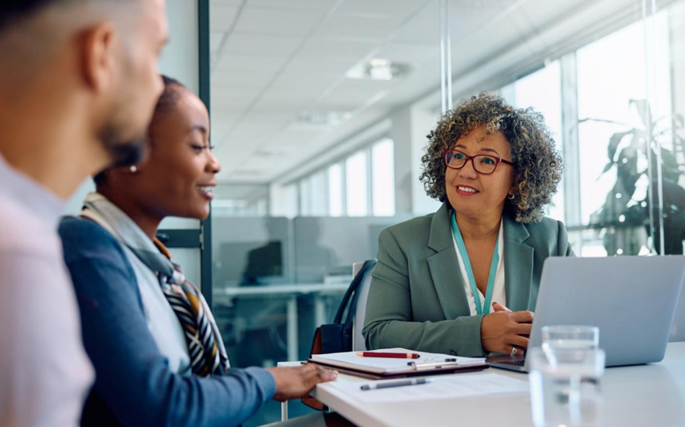 Three people sitting at a table talking.